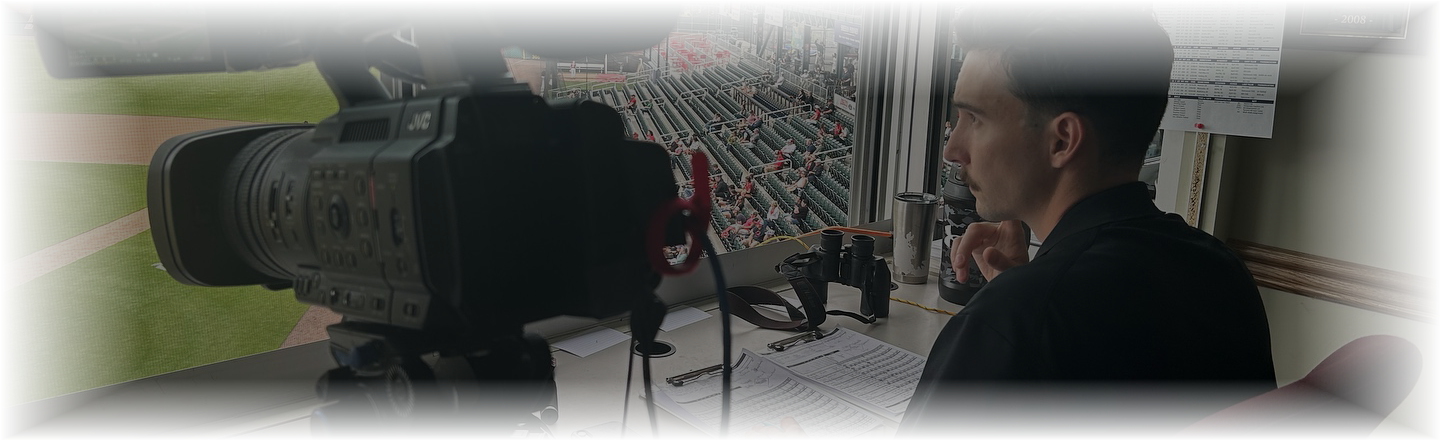 Berkley Stevens in the broadcast booth, camera trained on the field
